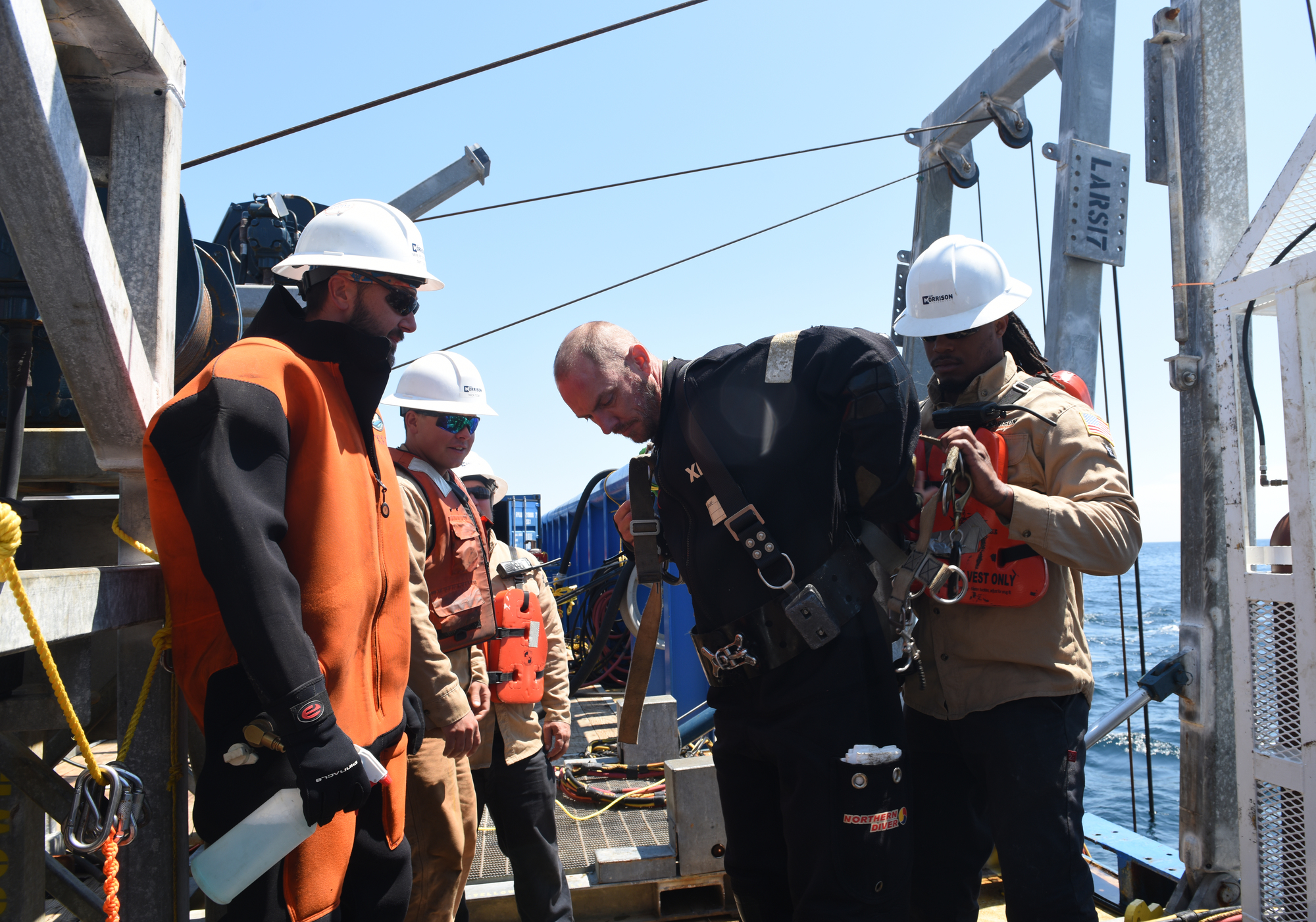 A team assists a diver as he prepares to enter the water and begin work 180 feet below the surface on the tanker Coimbra wreck, May 16, 2019. The U.S. Coast Guard has contracted Resolve Marine Group to conduct a full assessment of oil remaining on the Coimbra wreck, located approximately 30 miles southeast of Shinnecock, N.Y. If substantial oil still remains, and if feasible, the Coast Guard will work with Resolve Marine Group to remove oil from the wreck in order to reduce pollution risks to the environment. The Coimbra, a British-flagged supply ship, sunk off the coast of Long Island in January 1942 when a German U-boat torpedoed it. (U.S. Coast Guard photo by Chief Warrant Officer Allyson E.T. Conroy)