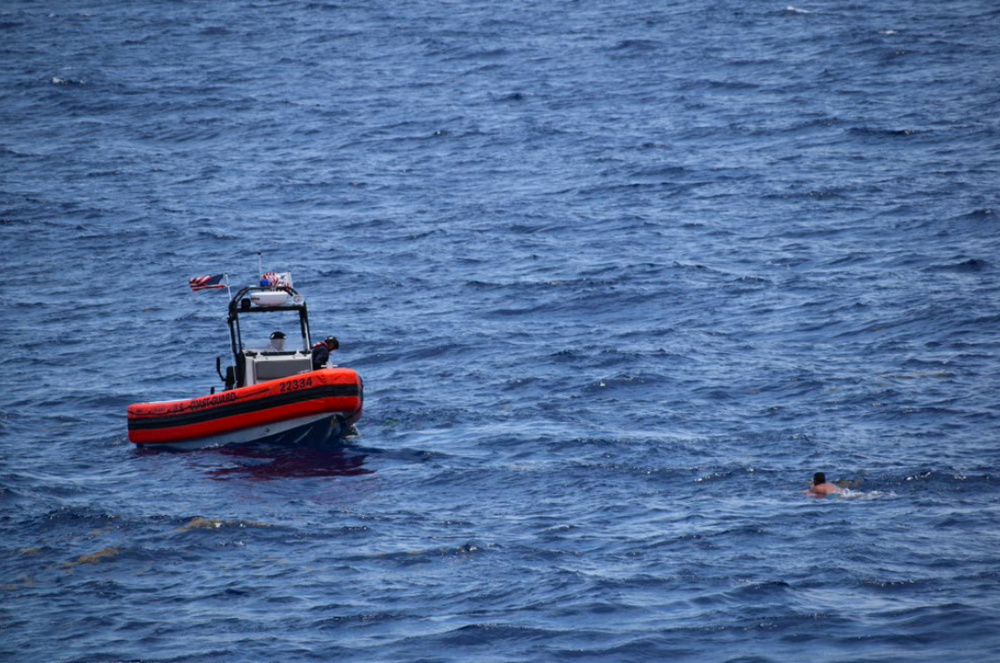 A small boat approaches a migrant in the water