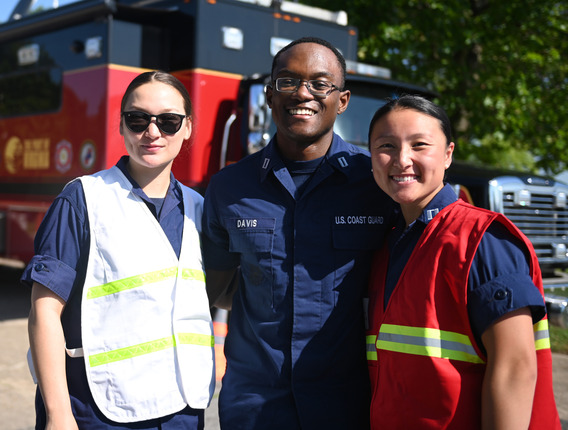 Three Coast Guard service members posing and smiling.