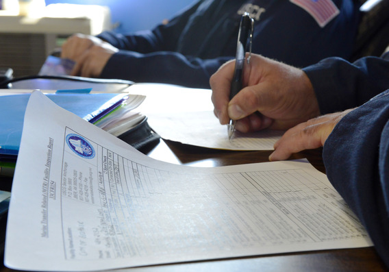 Close up of hands with Coast Guard service member writing on paper.