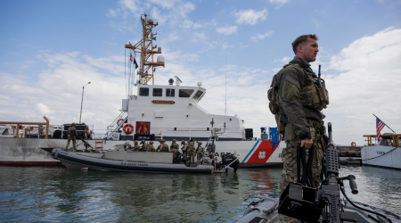 Coastie stands in front of a ship