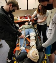 youth members help to splint the arm of patient 