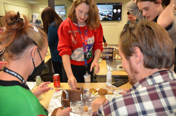 Region 8 staff gather around a table to build a gingerbread house. 