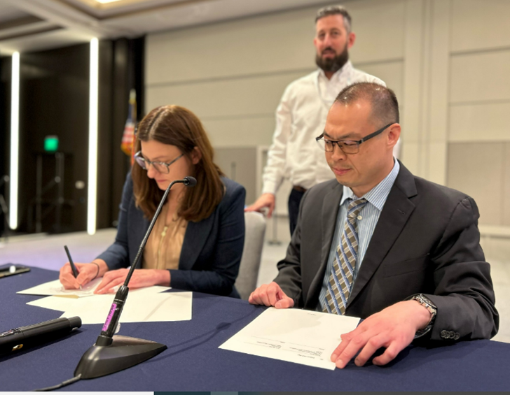 Two people signing a document. 