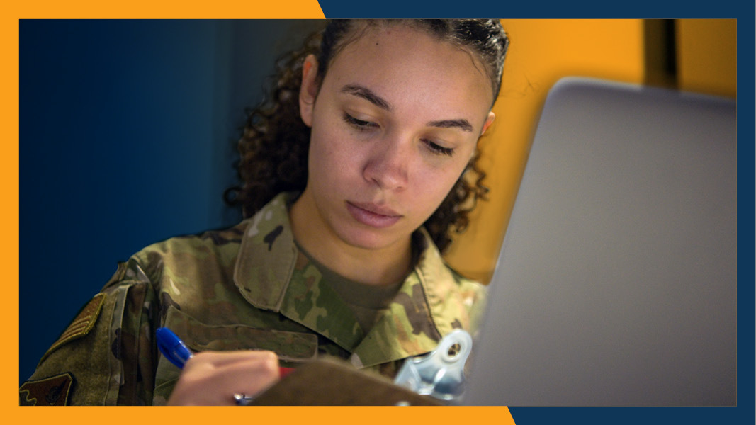 Service member looking at clipboard and laptop