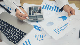 Person using a calculator and reviewing graphs