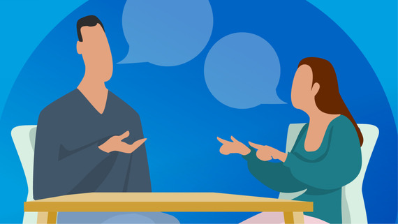 Man and woman seated at a table talking to each other