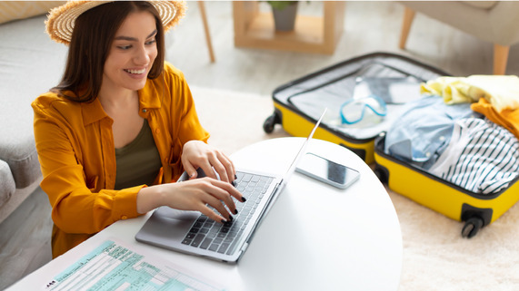Woman looking at laptop near suitcase