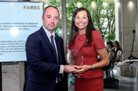 Catherine Jereza accepting the Champions of Puerto Rico award, standing alongside a presenter in front of an informational display.