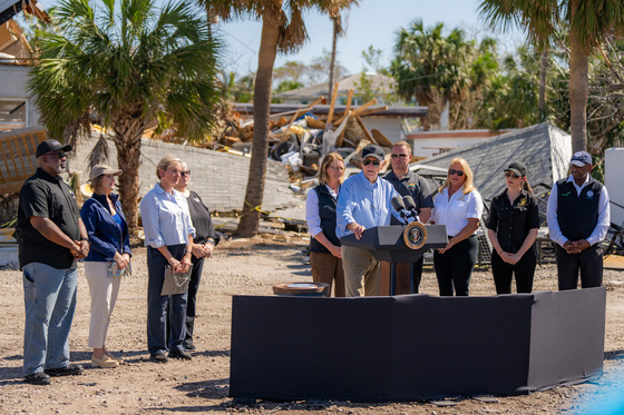 President Biden speaking on podium in front of building rubble