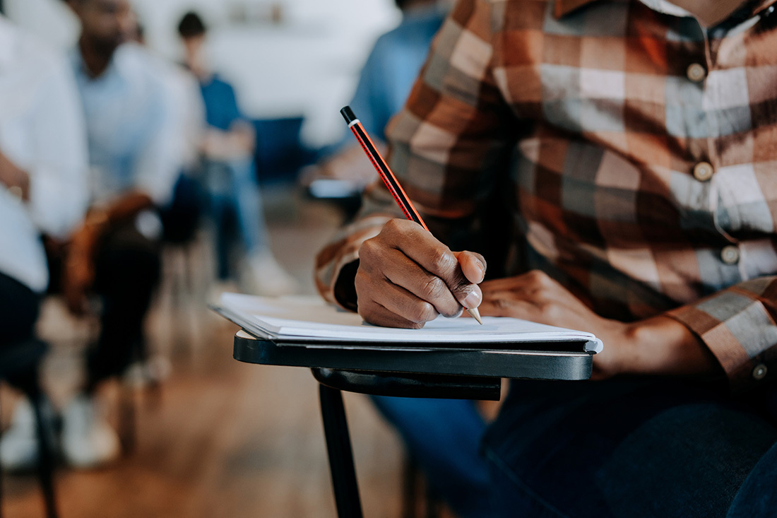 Person taking notes at desk in classroom