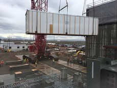 A large crane moves the first section of a 111-ton electrical powerhouse for the Waste Treatment Plant