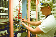 Technician Quinn Bragg installs new equipment as a part of a project to upgrade the phone services at the Waste Treatment and Immobilization Plant. 