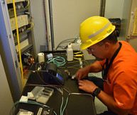An electrician installs fiber optic cables inside an electrical powerhouse for the Effluent Management Facility.