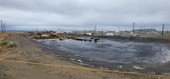 Workers install perforated piping on top of a plastic liner that makes up the floor of an evapotranspiration basin at the U Farm at the Hanford Site.