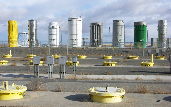 Several tall cylinders lined up in a row and painted different colors.
