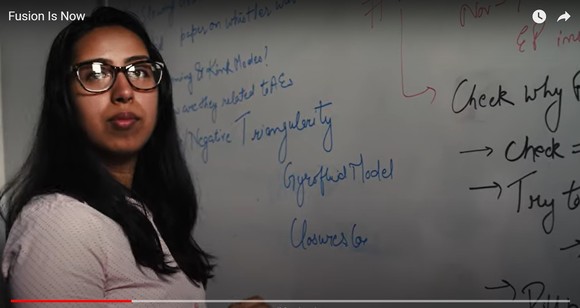 Photo of a Southeast Asian woman with glasses standing in front of a white board covered in equations