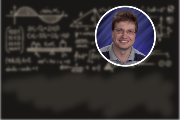 Photo of a white man in a polo shirt with a background of a blackboard with blurred images 