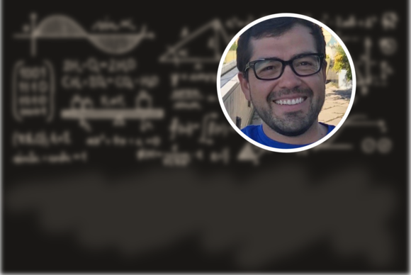 Headshot photo of Victor M. Zavala (a man with glasses) against a background of a blackboard with blurred equations 