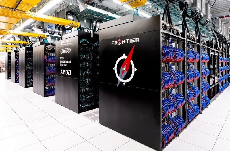 Photo of the Frontier supercomputer cabinets with their panels open, showing loops of blue and red writing