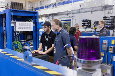Photo of the Vertical Test Area with Justin Kent and Jacob Harris (white men in polo shirts) with 3 people in the background