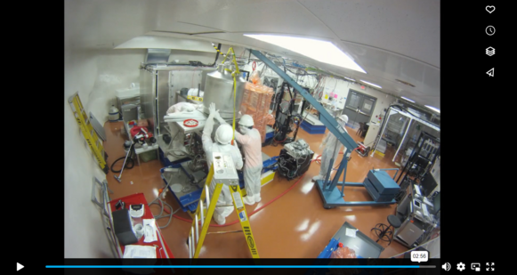 Screenshot of a video of the Majorana Demonstrator assembly, showing people in clean room suits putting together the machine