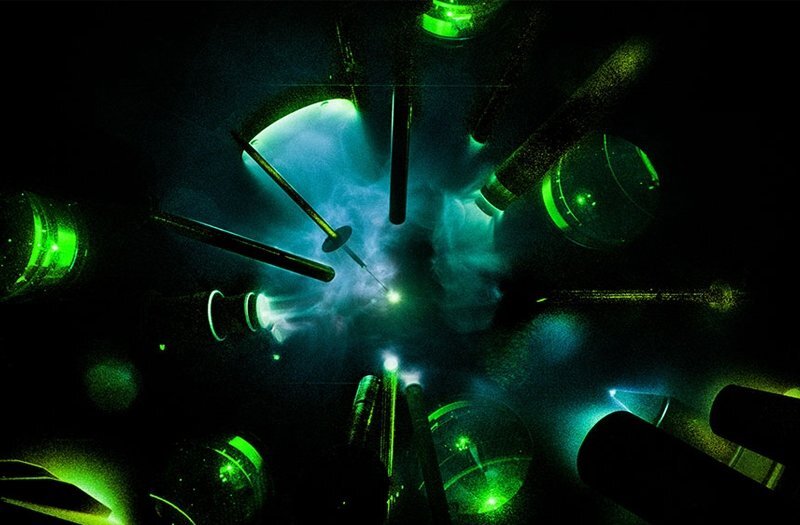 Laser devices pointed at a center point with gas illuminated by the lasers' green tint