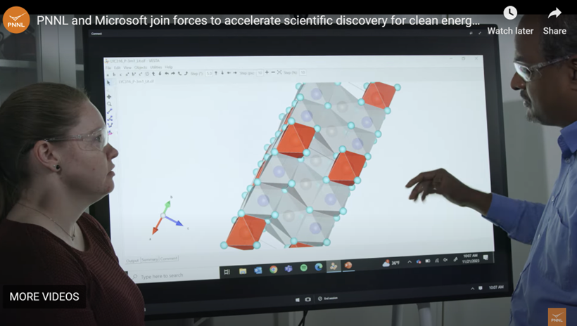 Two engineers (a South Asian man and a while woman, both in lab goggles) looking at a large computer screen with a molecular structure on it