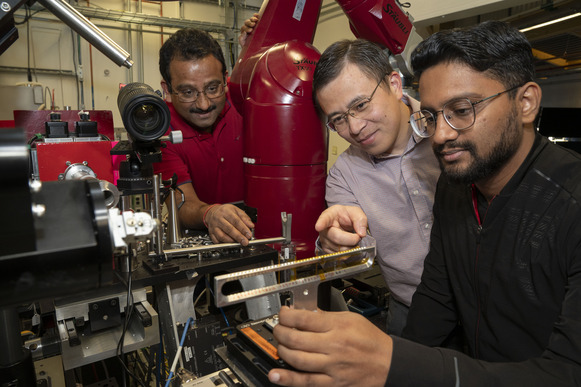 Sanjit Ghose (a South Asian man), Enyuan Hu (an East Asian man) and Muhammad Mominur Rahman (a South Asian man) looking at a measuring instrument