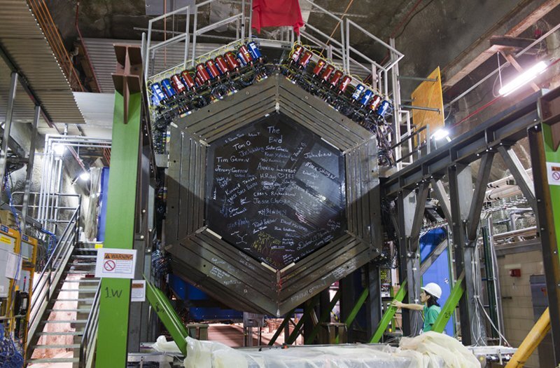 The particle detector for the MINERvA experiment. It is a large hexagon with blue and red cylinders along the top and signatures on the front.