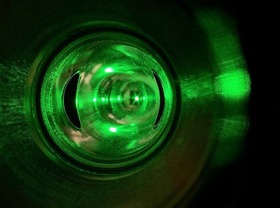 The Compton polarimeter’s laser system, used to measure electrons’ parallel spin. It has a ring-like device with a green glow.