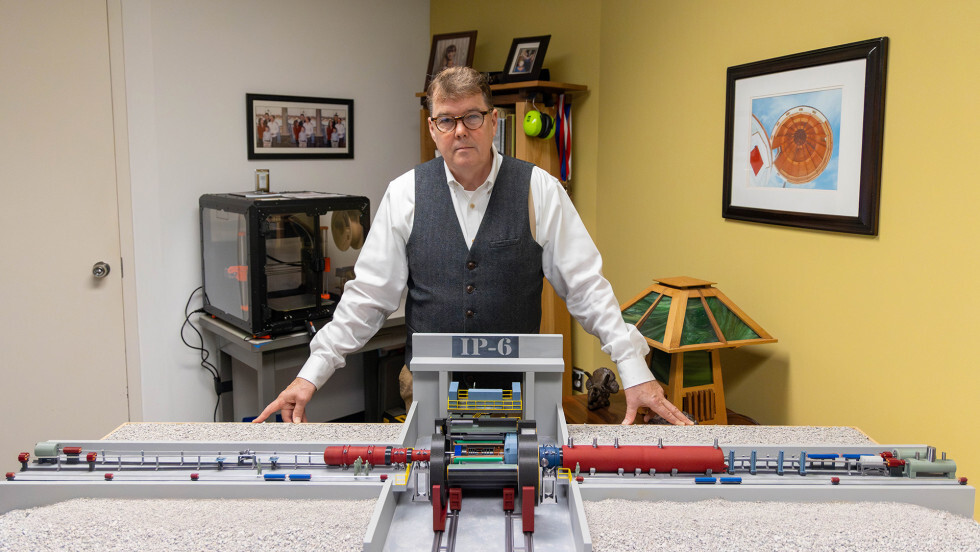 Walt Akers (a white man in a gray vest) standing behind a table with a 3D printed model of part of the Electron-Ion Collider