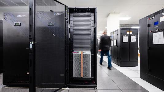 A person walking between cabinets of supercomputers