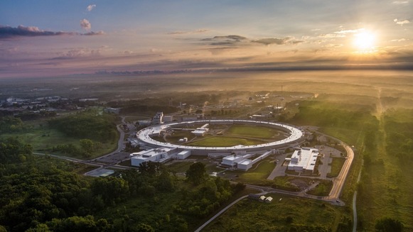 An aerial view of the Advanced Photon Source (which is a large circular building) at sunset