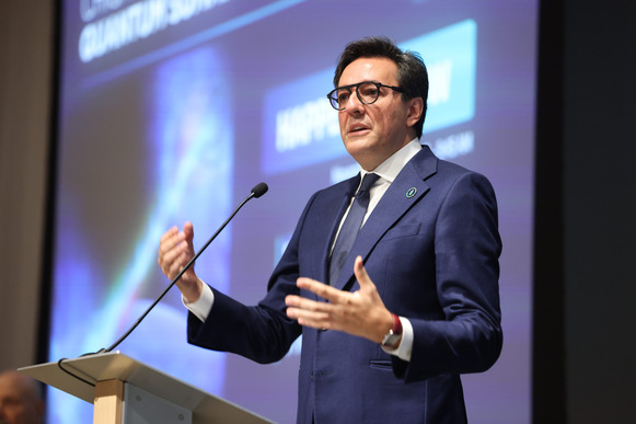 Darío Gil speaking at a podium with a large screen behind him