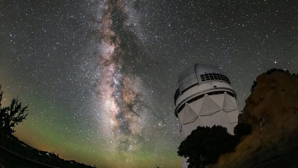 Image of an observatory on a cliff with a very clear night sky with the Milky Way in the background