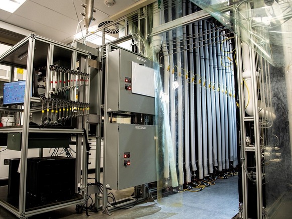 A lab filled with machinery, including floor-to-ceiling tubes and a rack of wretches 
