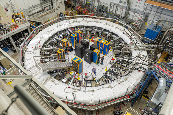 Top-down view of the Muon g-2 experiment, which has a large white ring with computer terminals inside of it