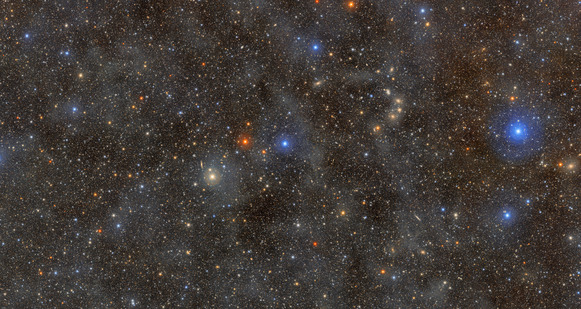 Cosmic photo of an ocean of stars, with several prominent bright blue and yellow galaxies and a number of dimmer ones in the background