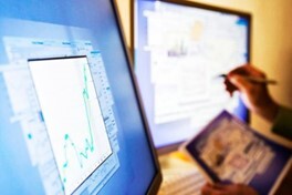 Two computer monitors with graphs and tables