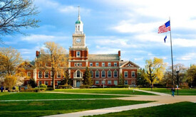 School building with a clock tower and flag in front