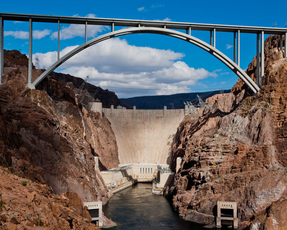 The Hoover Dam towers over the Colorado River under a bright blue sky