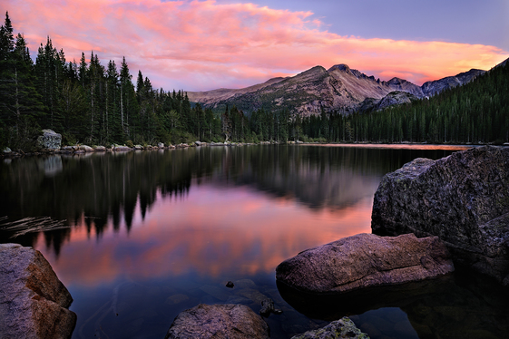 A mountain peak reflected in a lake as the sky turns pink