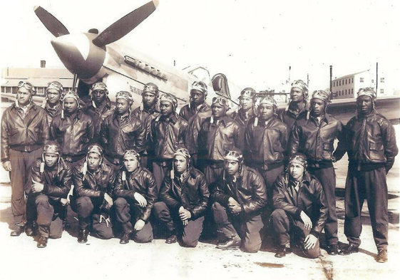 Historic photo of two lines of World War 2 African American pilots in flight gear posing in front of a fighter plane.