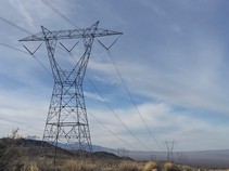 High voltage power line and tower on a desert hill.