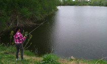 An angler fishing by a lake. 