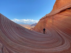 A person hiking on a slick rock formation. 