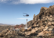 Helicopter dropping water on a fire on a rocky mountain