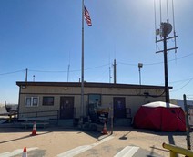 A small building with a flagpole and antenna out front.