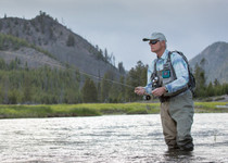 A man stands in a lake fly fishing.